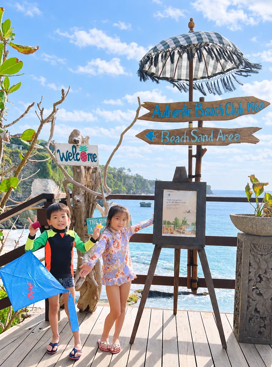 海辺のビーチクラブで、凧を持ってポーズをとる子どもたち